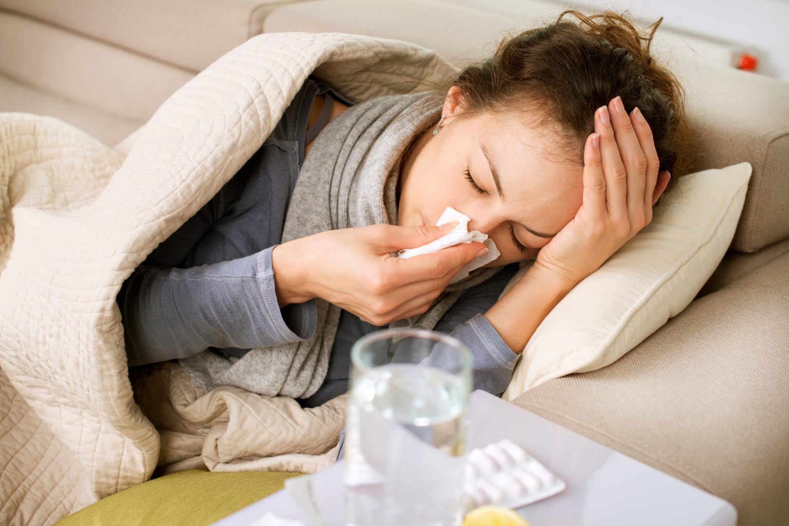 lady ill in bed with a cold and tissue in her hand